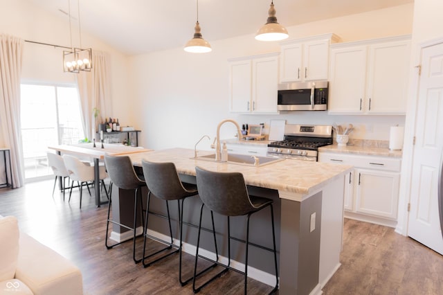 kitchen featuring appliances with stainless steel finishes, a breakfast bar, a sink, an island with sink, and wood finished floors