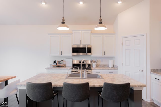 kitchen featuring stainless steel appliances, a kitchen breakfast bar, white cabinetry, and a sink