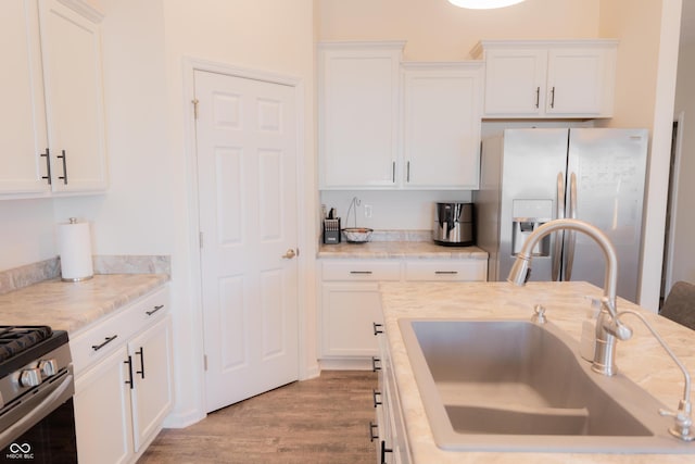kitchen featuring white cabinets, stainless steel appliances, a sink, and light countertops