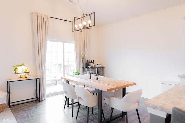dining space with wood finished floors, a chandelier, and high vaulted ceiling