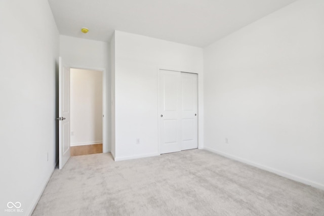 unfurnished bedroom with carpet, baseboards, and a closet