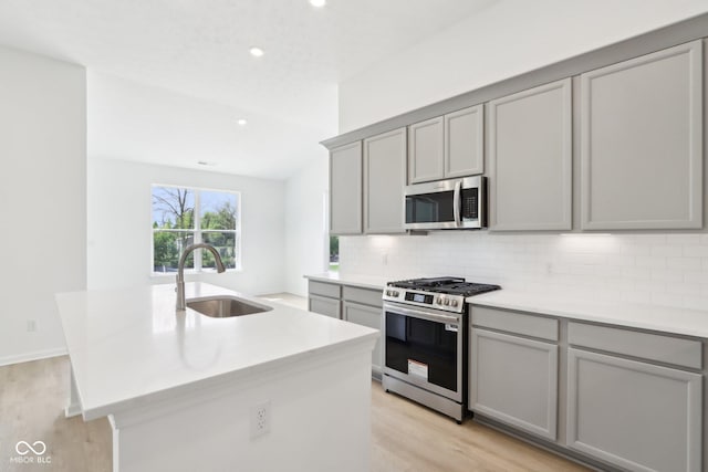kitchen featuring appliances with stainless steel finishes, gray cabinetry, a sink, and recessed lighting