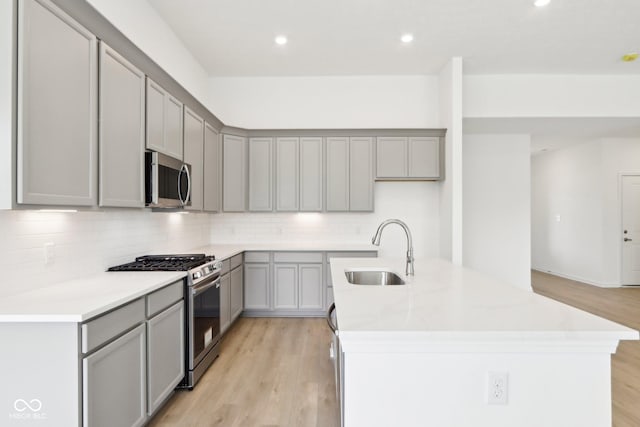 kitchen with appliances with stainless steel finishes, a sink, gray cabinets, and recessed lighting
