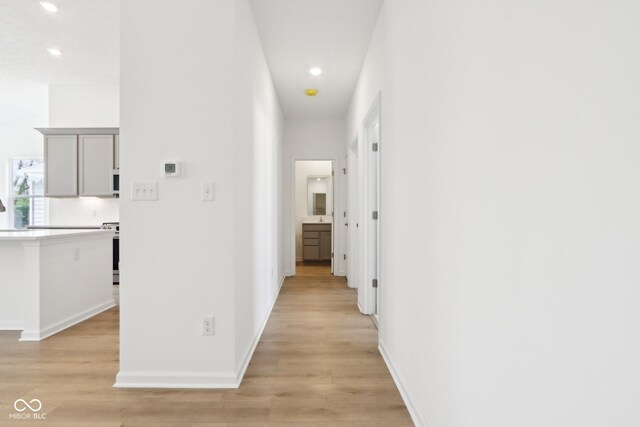hallway with recessed lighting, light wood finished floors, and baseboards