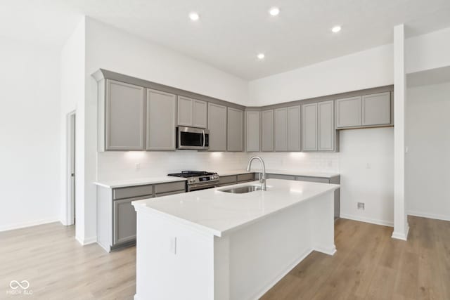 kitchen with stainless steel appliances, a sink, gray cabinets, backsplash, and recessed lighting
