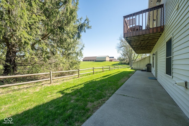 view of yard with fence, a patio, and a balcony