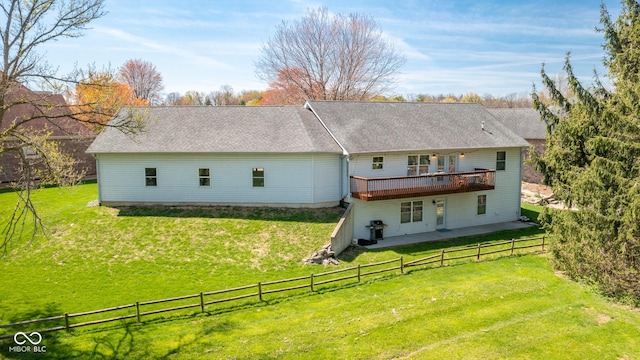 back of property with a wooden deck, a fenced backyard, roof with shingles, and a yard