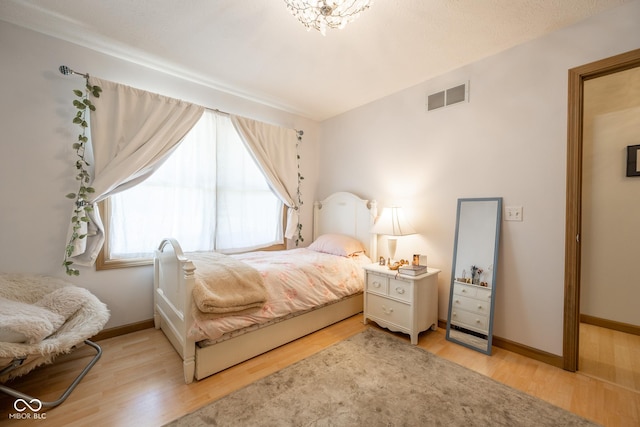 bedroom featuring wood finished floors, visible vents, and baseboards