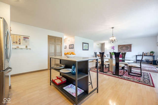 dining area with light wood-style flooring, baseboards, and an inviting chandelier