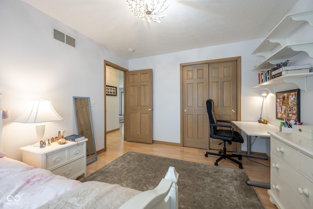 bedroom with light wood-style floors, baseboards, visible vents, and a closet