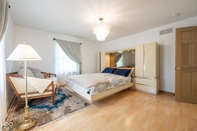 bedroom with baseboards, a chandelier, visible vents, and light wood-type flooring