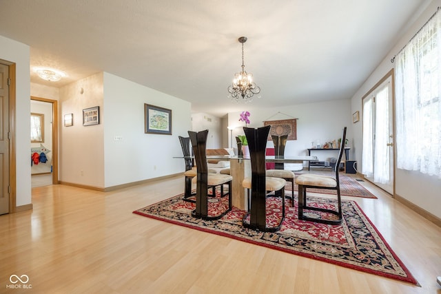 dining area featuring baseboards, a notable chandelier, and light wood-style floors