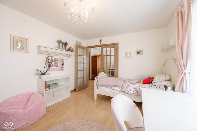 bedroom featuring an inviting chandelier, french doors, visible vents, and light wood-style flooring