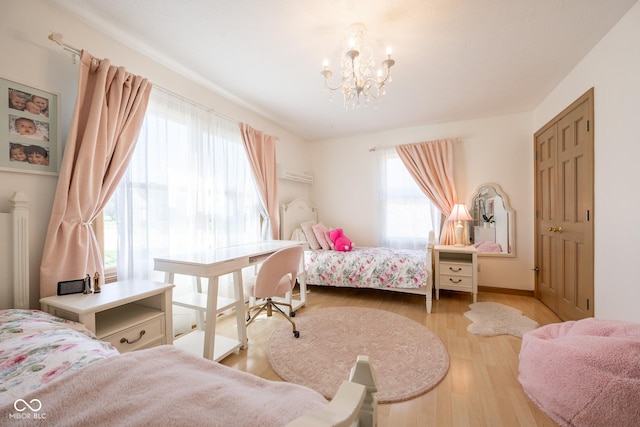 bedroom featuring baseboards, wood finished floors, and an inviting chandelier