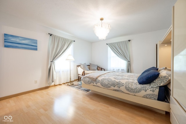 bedroom with baseboards, a chandelier, and wood finished floors