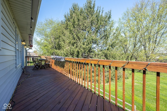 wooden deck featuring a lawn and outdoor dining space