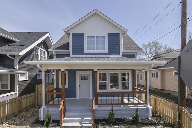 view of front of property with a porch, a shingled roof, and fence