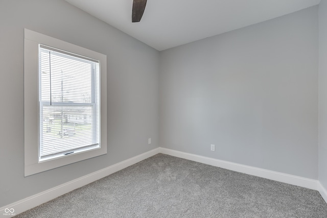 carpeted spare room with ceiling fan and baseboards