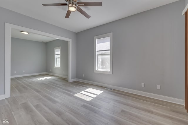 spare room featuring light wood-type flooring, ceiling fan, and baseboards