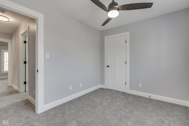carpeted empty room featuring ceiling fan and baseboards