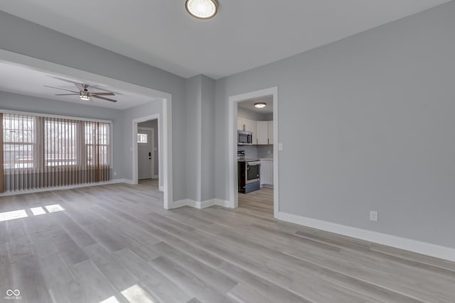 unfurnished living room featuring baseboards, light wood finished floors, and ceiling fan