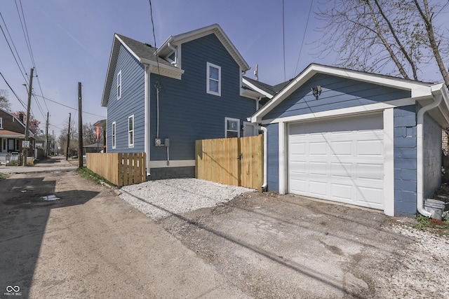 exterior space with an outbuilding, fence, a garage, and aphalt driveway