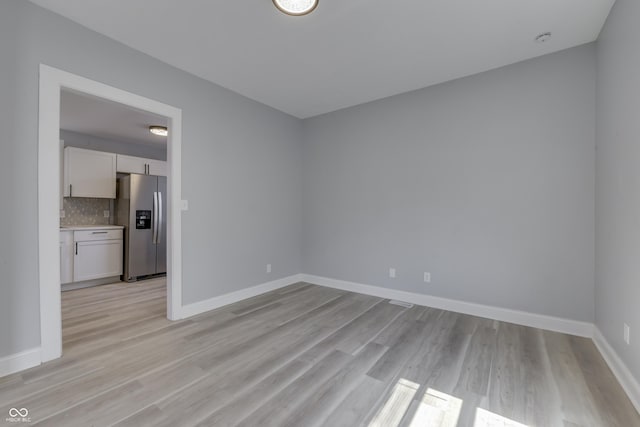 unfurnished room featuring baseboards and light wood finished floors
