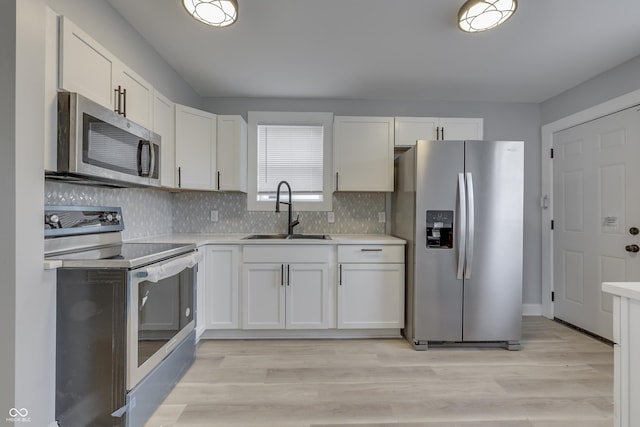 kitchen with tasteful backsplash, white cabinetry, light countertops, a sink, and stainless steel appliances