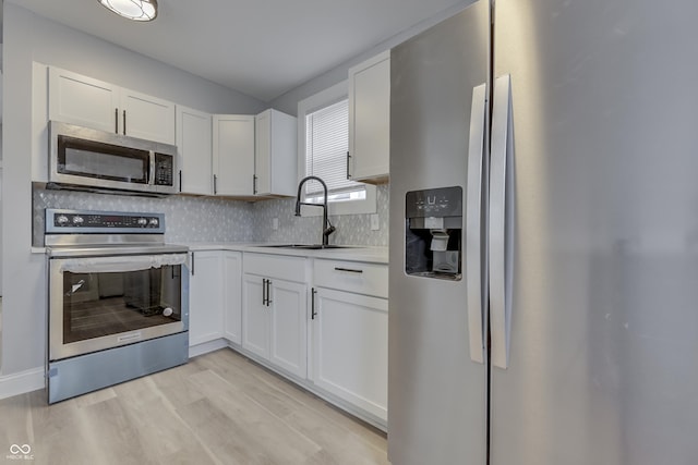 kitchen with a sink, light countertops, white cabinetry, stainless steel appliances, and backsplash