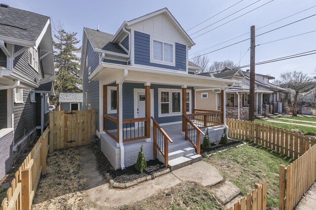view of front of home featuring a porch, fence, and a shingled roof