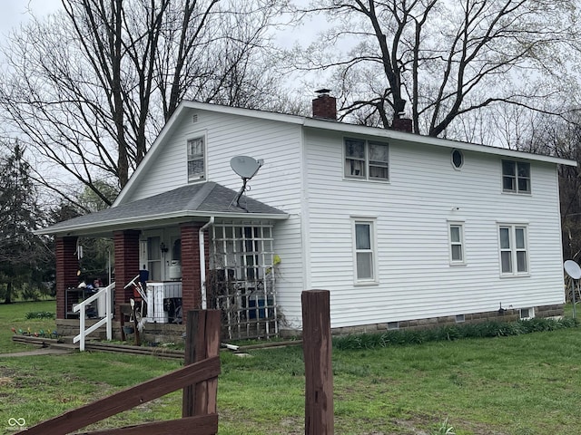view of front of property with a front yard, covered porch, and a chimney