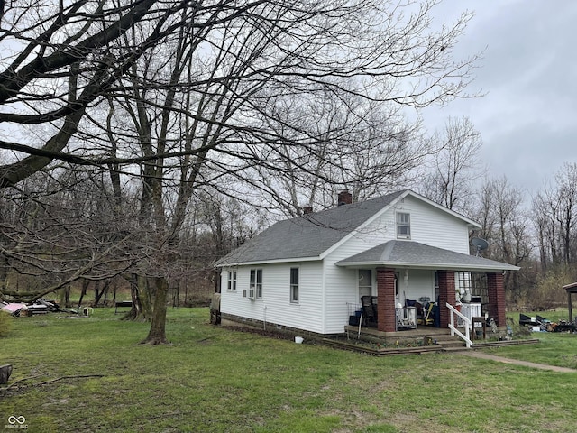 bungalow with covered porch, a chimney, a shingled roof, and a front yard