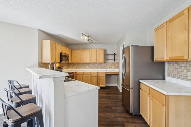 10303 Memorial Knoll Dr, Indianapolis, IN 46234 - kitchen with appliances with stainless steel finishes, a peninsula, light brown cabinetry, dark wood-type flooring, and a breakfast bar area