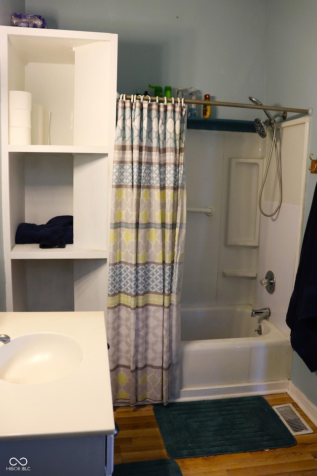 bathroom with shower / bath combo with shower curtain, visible vents, a sink, and wood finished floors
