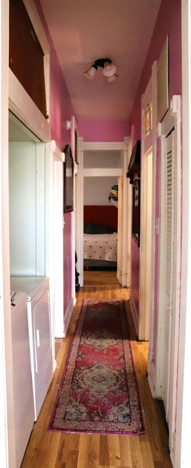 hall with washer and clothes dryer and wood finished floors