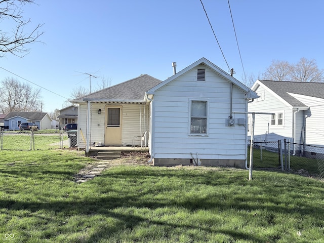 1804 W 15th St, Muncie, IN 47302 - back of house featuring a shingled roof, a gate, fence, and a lawn
