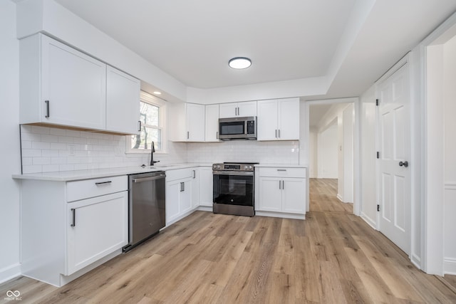 4106 Armon Ct, Carmel, IN 46033 - kitchen with light wood-style flooring, white cabinets, appliances with stainless steel finishes, a sink, and light countertops