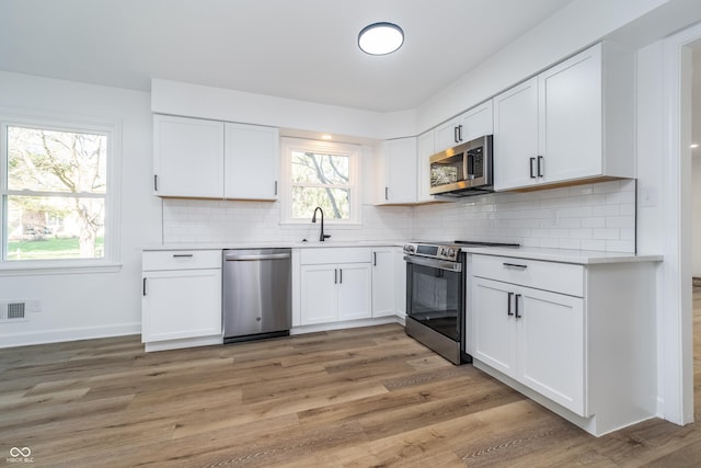 4106 Armon Ct, Carmel, IN 46033 - kitchen featuring white cabinets, a sink, light countertops, appliances with stainless steel finishes, and light wood-style flooring