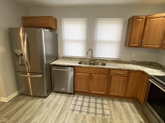 1546 Kappes St, Indianapolis, IN 46221 - kitchen with light stone countertops, light wood-style flooring, brown cabinetry, a sink, and stainless steel appliances