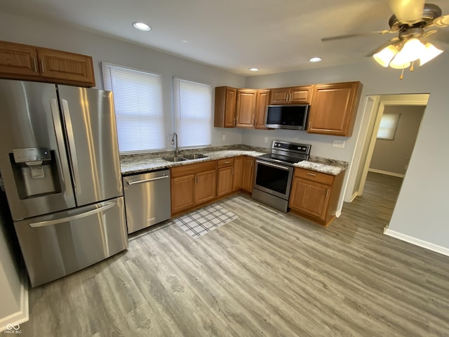 1546 Kappes St, Indianapolis, IN 46221 - kitchen with light stone countertops, light wood-style floors, brown cabinetry, stainless steel appliances, and a sink