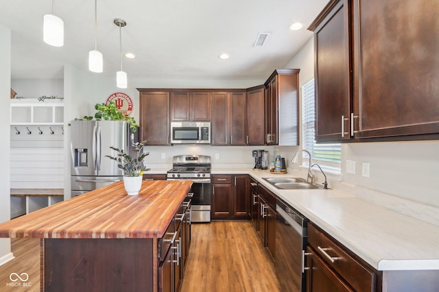 kitchen with butcher block countertops, appliances with stainless steel finishes, wood finished floors, and a sink