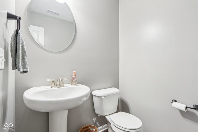 half bath with visible vents, toilet, and baseboards