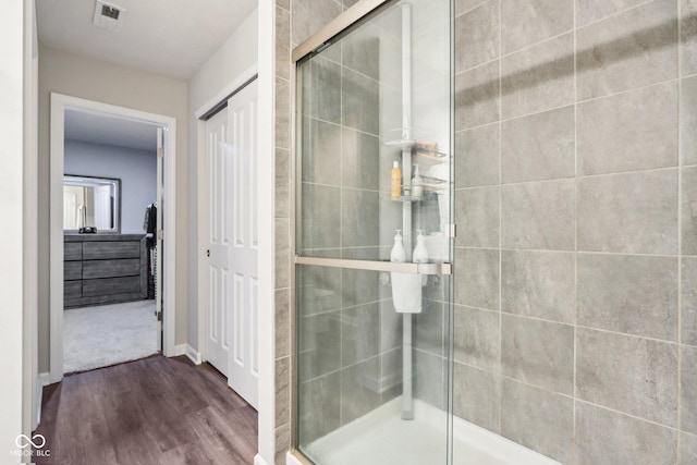bathroom featuring visible vents, baseboards, a shower stall, and wood finished floors
