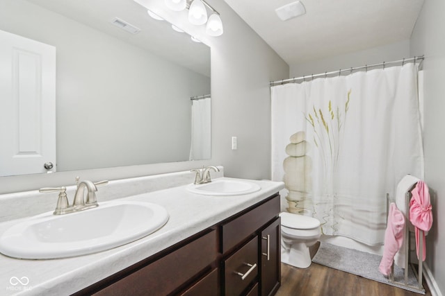 bathroom with toilet, wood finished floors, a sink, and visible vents