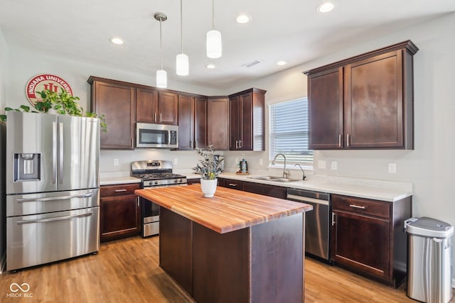 kitchen with dark brown cabinetry, wooden counters, stainless steel appliances, light wood finished floors, and a sink