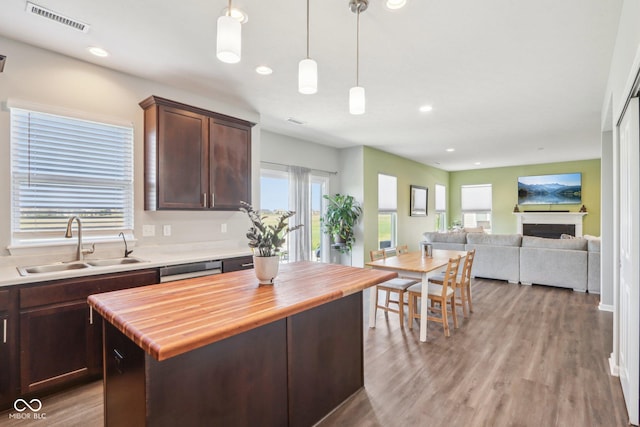 kitchen with dark brown cabinetry, wooden counters, visible vents, dishwasher, and a sink