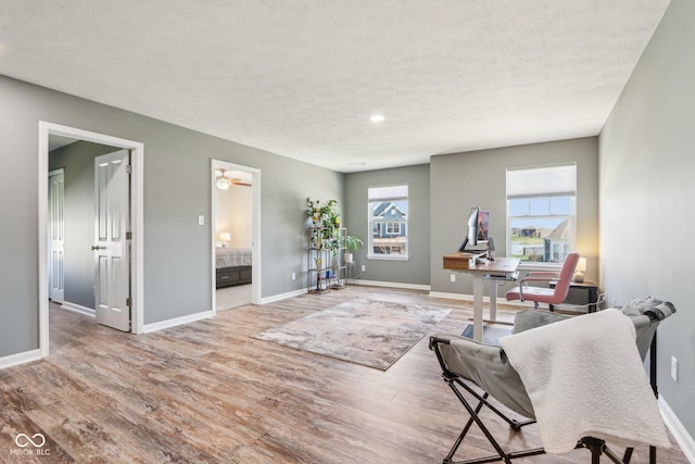 interior space featuring a textured ceiling, light wood finished floors, and baseboards