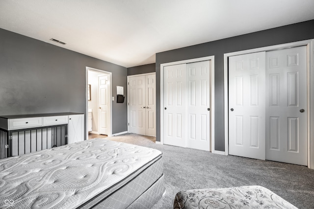 bedroom with baseboards, light carpet, two closets, and visible vents
