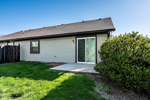 back of property featuring a yard, a patio, fence, and a shingled roof