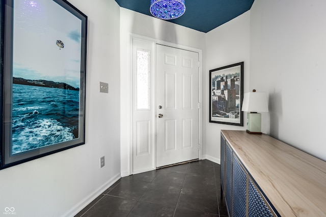 entryway with dark tile patterned flooring and baseboards